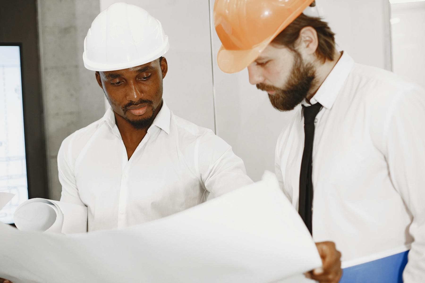 Two engineers reviewing detailed blueprints indoors